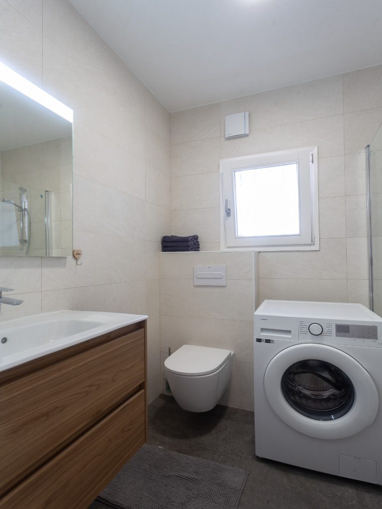 Bathroom with sink, shower and washing machine at Villa Vino in Pedreguer