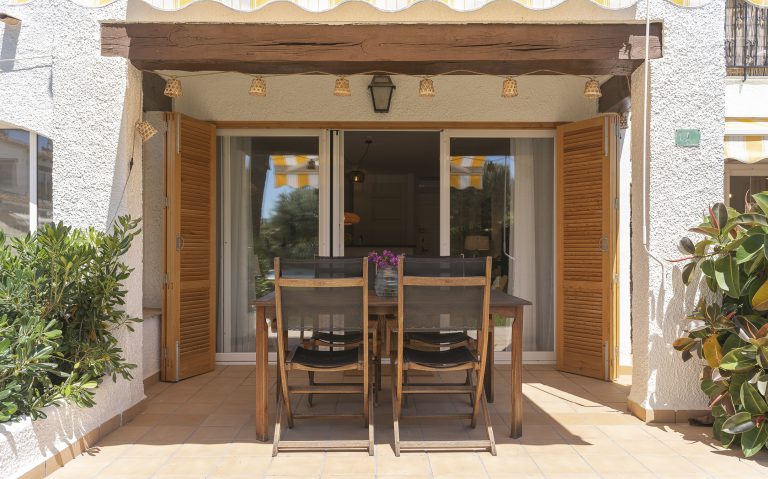 Covered terrace with wooden dining table at apartment Retiro Sol A1 in Dénia